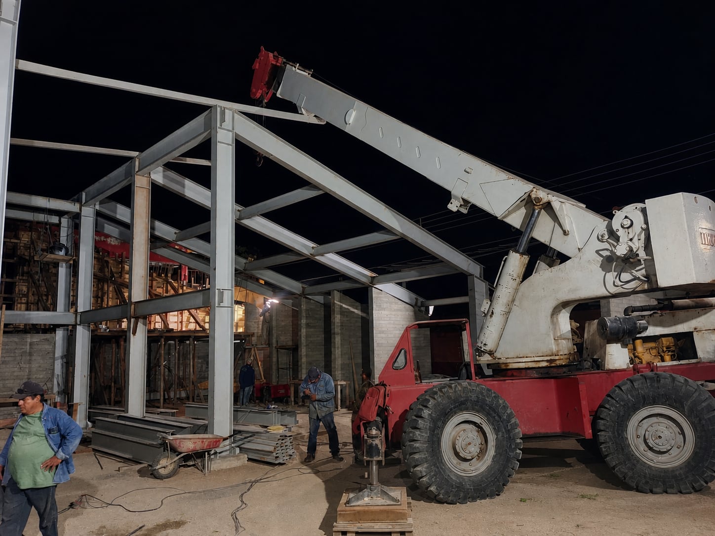 Montaje nocturno de estructura metálica con grúa